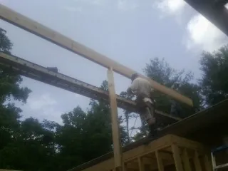Carpenter setting a ridge beam over a new addition frame — Ice Dam Removal by Roofing Brothers in Big Lake