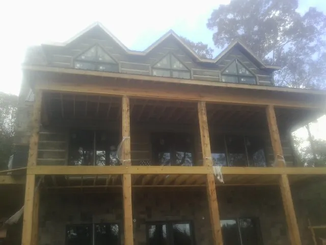 Dormers and porch framing on a large log home under construction — Roof Coating work by our crew in Big Lake