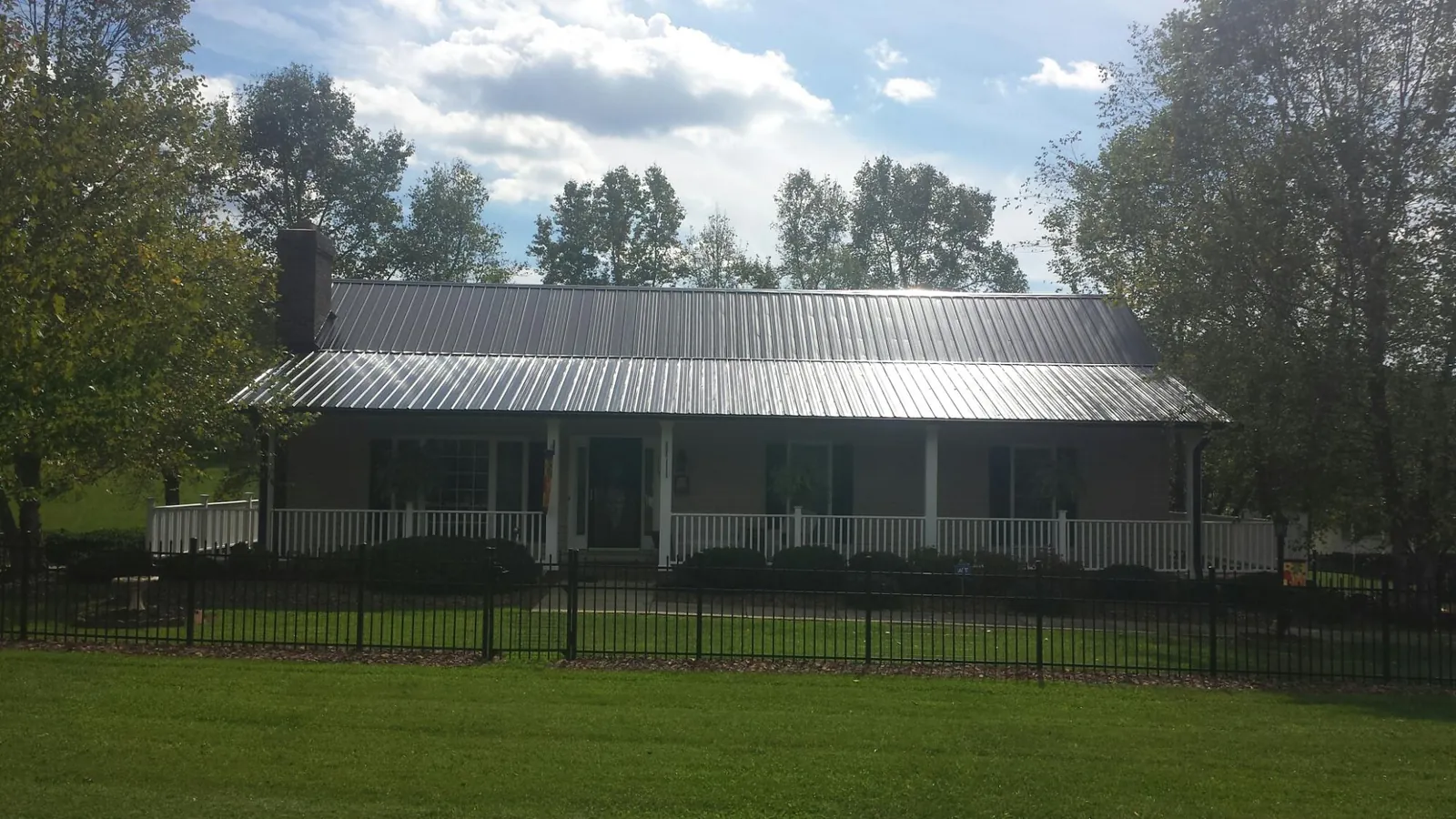 Gray metal roof on a brick ranch with a full width front porch — Gutter Guard Installation work by our crew in Big Lake