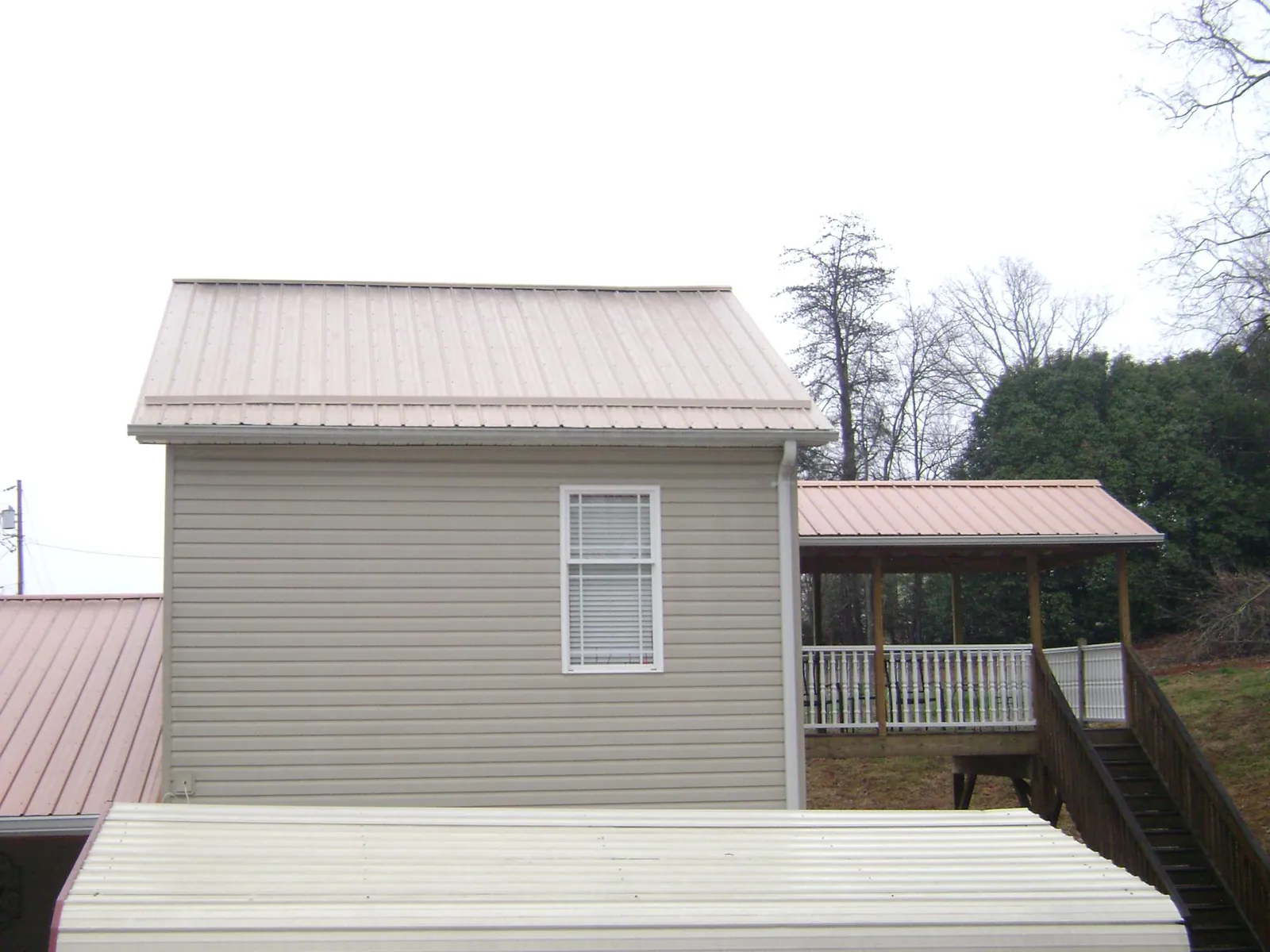 Tan metal roofs on a two story addition and attached porch, from a Roof Replacement job in Big Lake