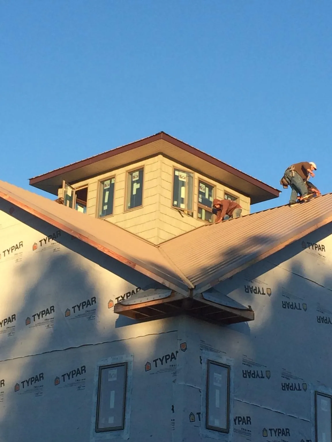 Roofers working around a rooftop cupola on a new metal roof at sunset — Roof Waterproofing in Big Lake by Roofing Brothers